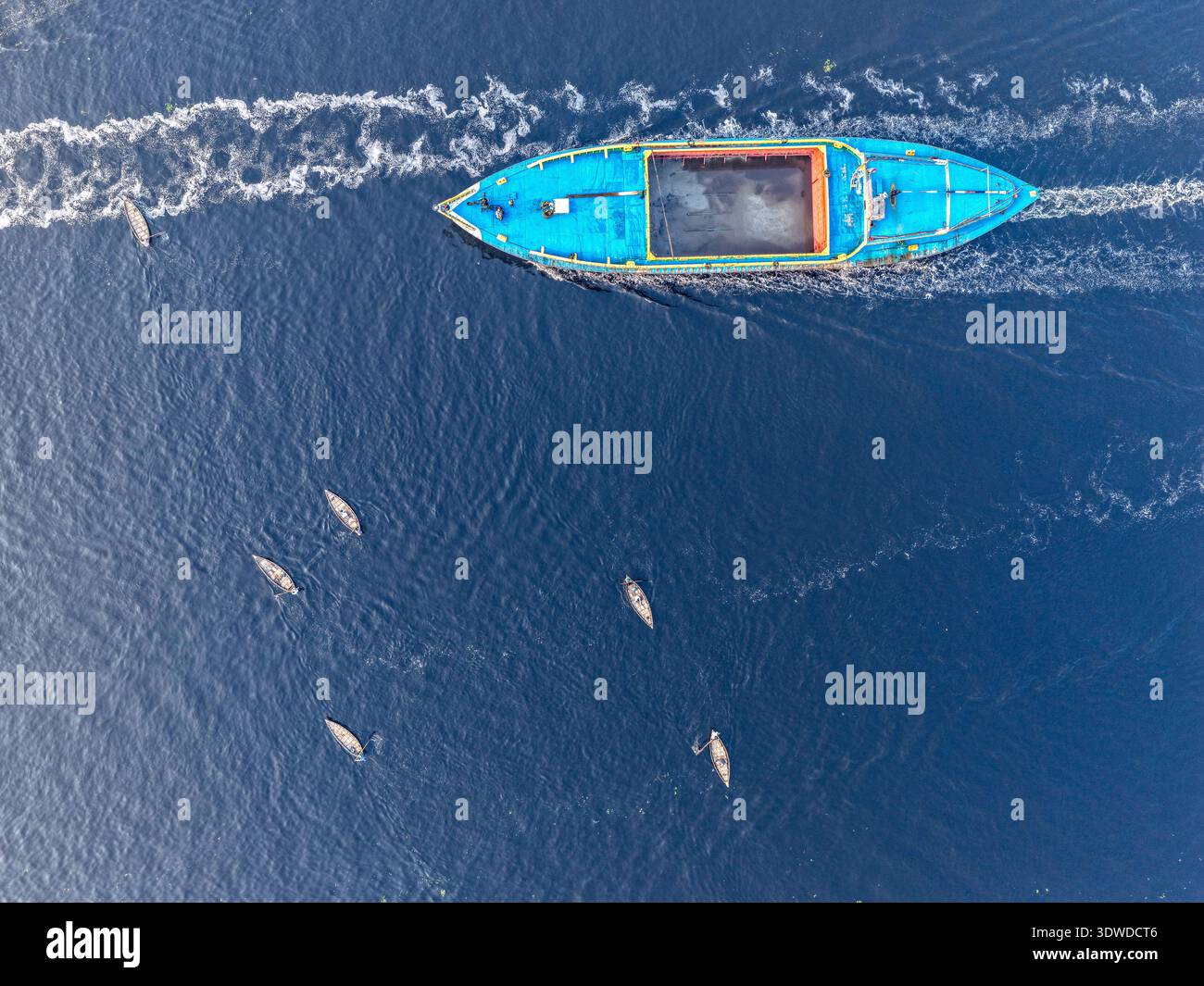 Dacca, Bangladesh - 23 gennaio 2026: Vista aerea di una barca turchese che naviga sulle acque blu scuro del fiume Buriganga, lasciando un sentiero bianco Foto Stock