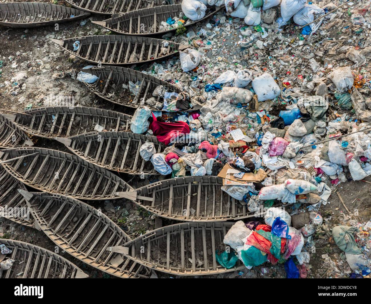 Dhaka, Bangladesh - 23 gennaio 2026: Vista aerea delle barche piene di rifiuti e detriti sul fiume Buriganga, un netto contrasto tra decadimento e resilienza Foto Stock