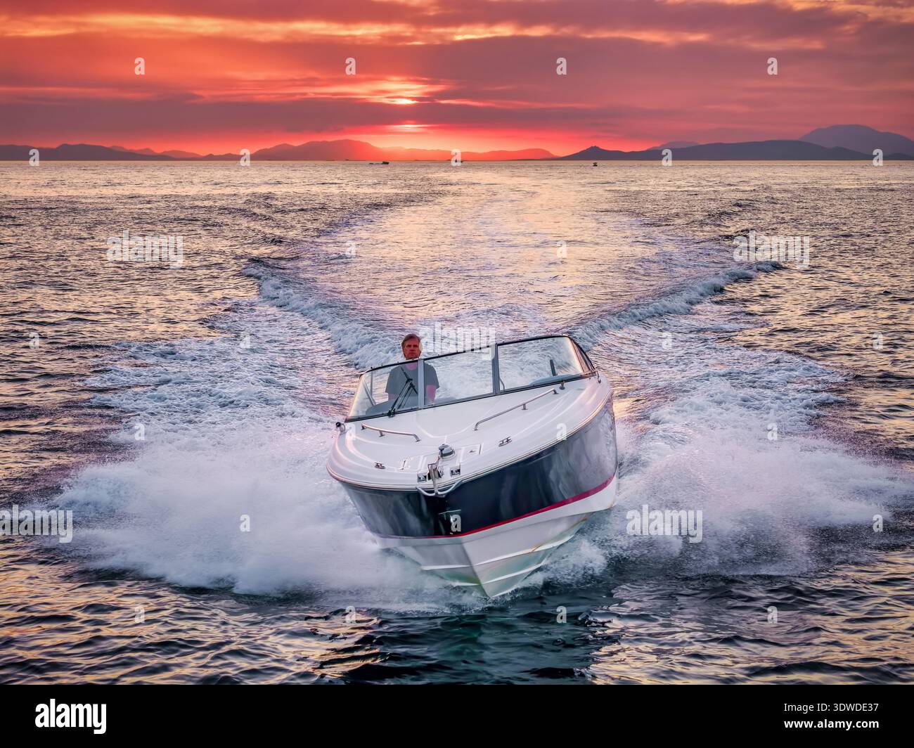 Vista frontale aerea di un motoscafo che naviga sull'oceano durante il tramonto, spruzza onde e acqua, surf e bolle Foto Stock
