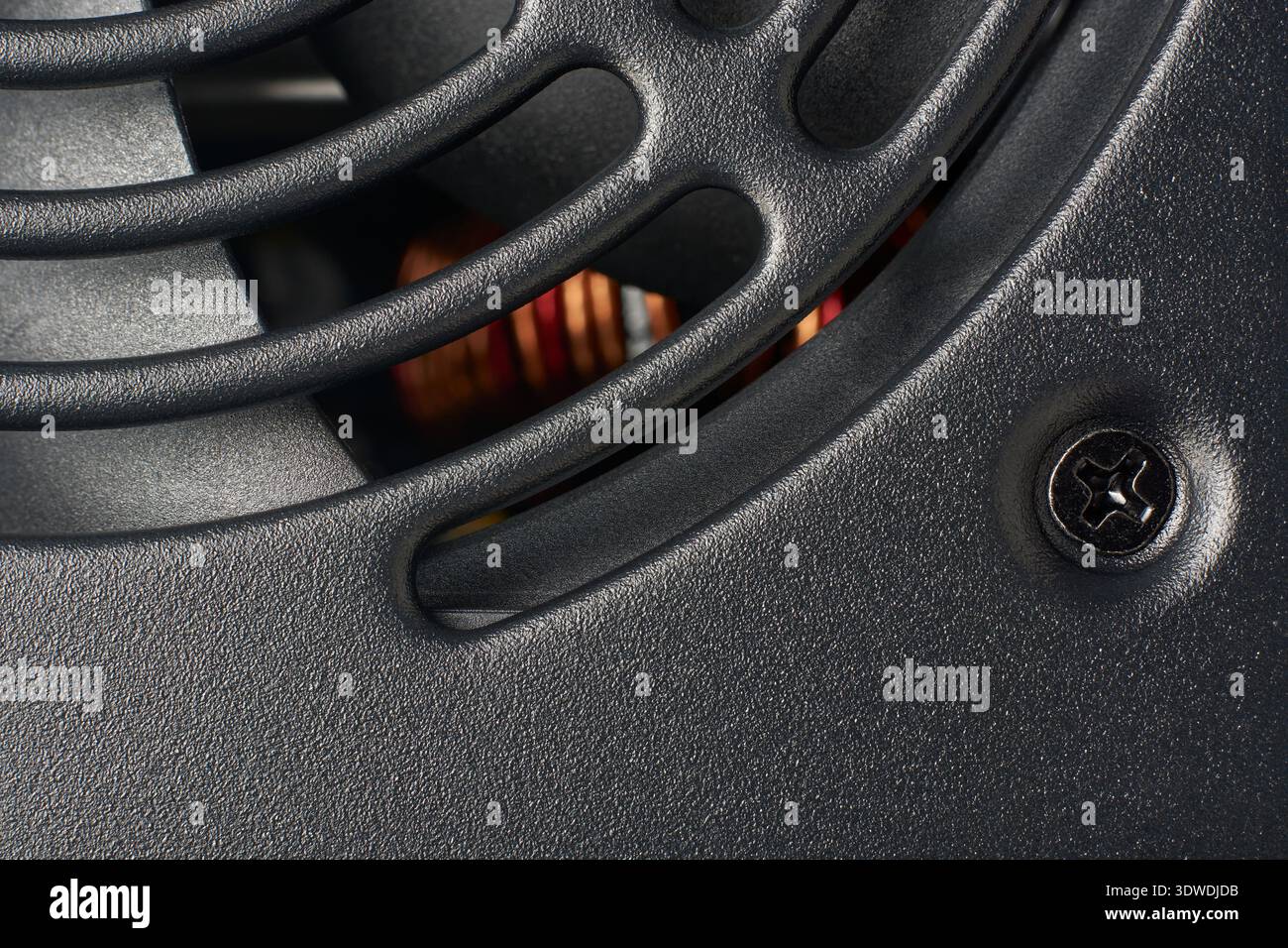 primo piano della superficie della griglia della ventola dell'alimentatore in pc nero opaco, prese d'aria curve e vite di montaggio nera sull'involucro protettivo, struttura completa del telaio Foto Stock