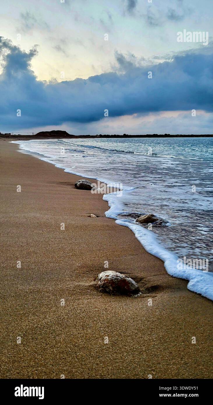 Idilliaca e tranquilla spiaggia sulla Costa Brava con onde bianche e spumeggianti che si infrangono sulla riva in una luce soffusa e accogliente del mattino. Foto Stock