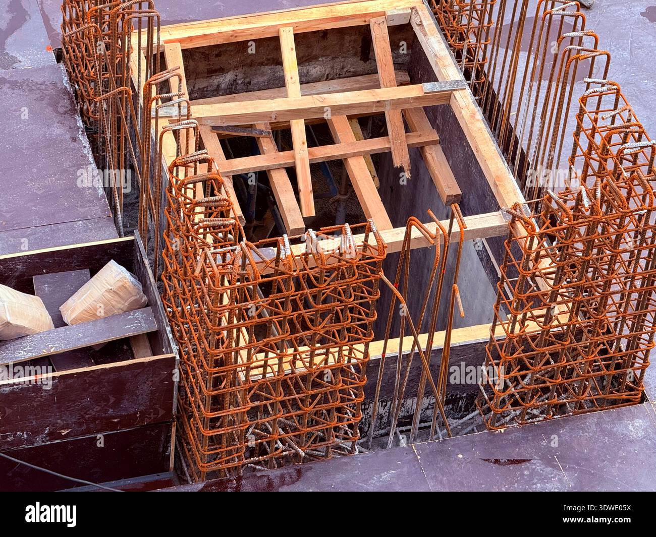 Un'immagine che mostra l'intricato processo di costruzione di travi in cemento armato, evidenziando i rinforzi per armature e i supporti in legno all'inizio del c Foto Stock