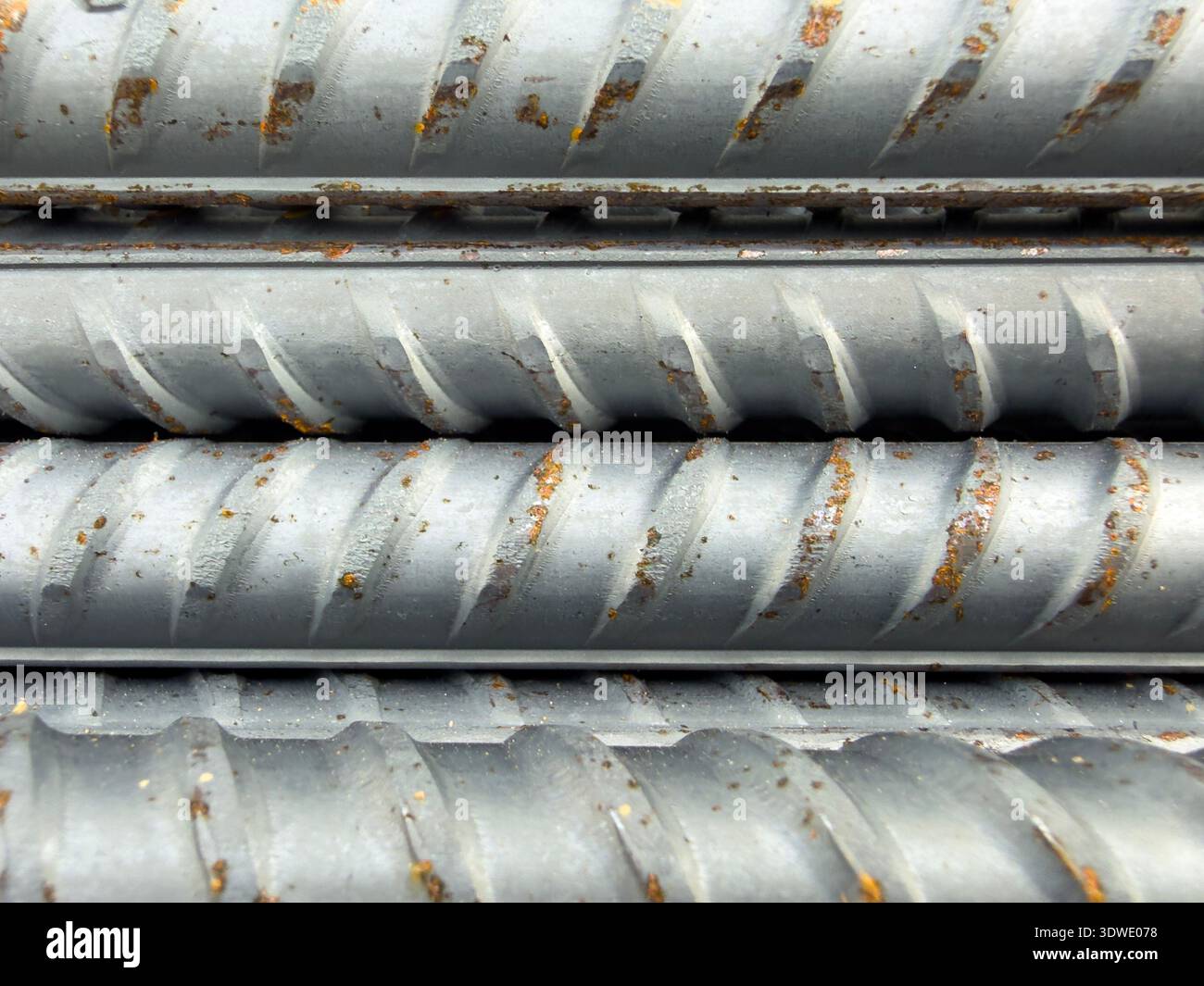 Un'immagine dettagliata ravvicinata delle barre di ferro di rinforzo in metallo testurizzato, che mostrano la loro superficie rigata, essenziale per la costruzione e il supporto strutturale Foto Stock