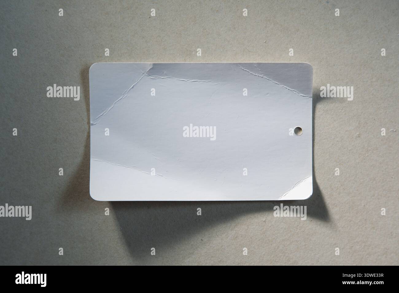 Carta bianca con etichetta a prezzo spiegazzata vuota su sfondo bianco sporco Foto Stock