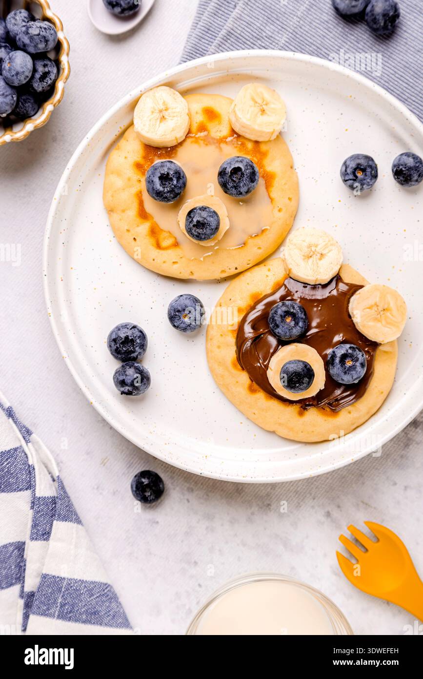 Una deliziosa colazione con soffici pancake conditi con mirtilli freschi e fette di banana. Ideale per un nutriente pasto mattutino o una bruna dolce Foto Stock