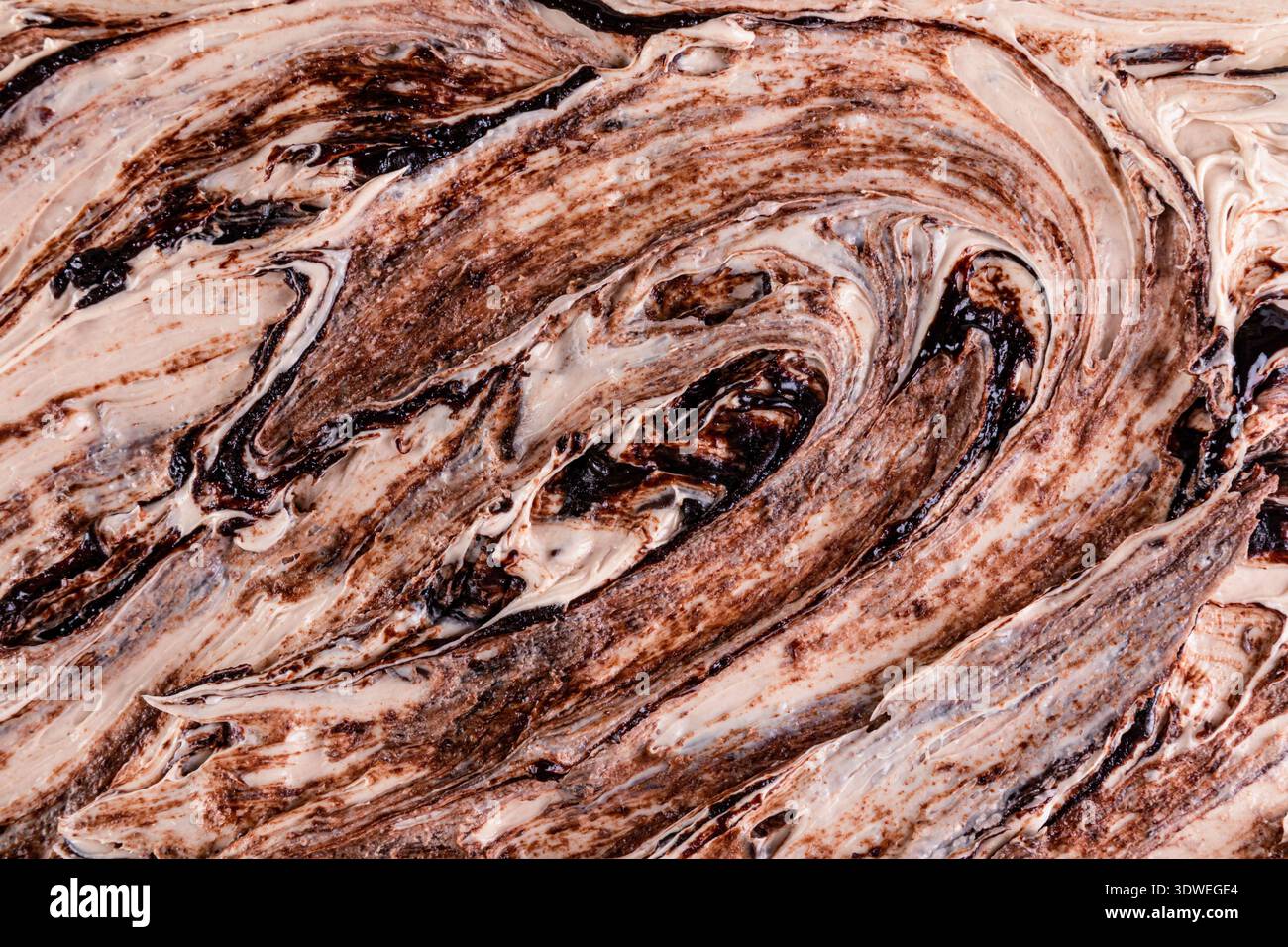 Una vista ravvicinata di una ricca consistenza di gelato al cioccolato, che mostra cremosi vortici di cioccolato con motivi intricati, catturando l'indulgente e la bocca Foto Stock