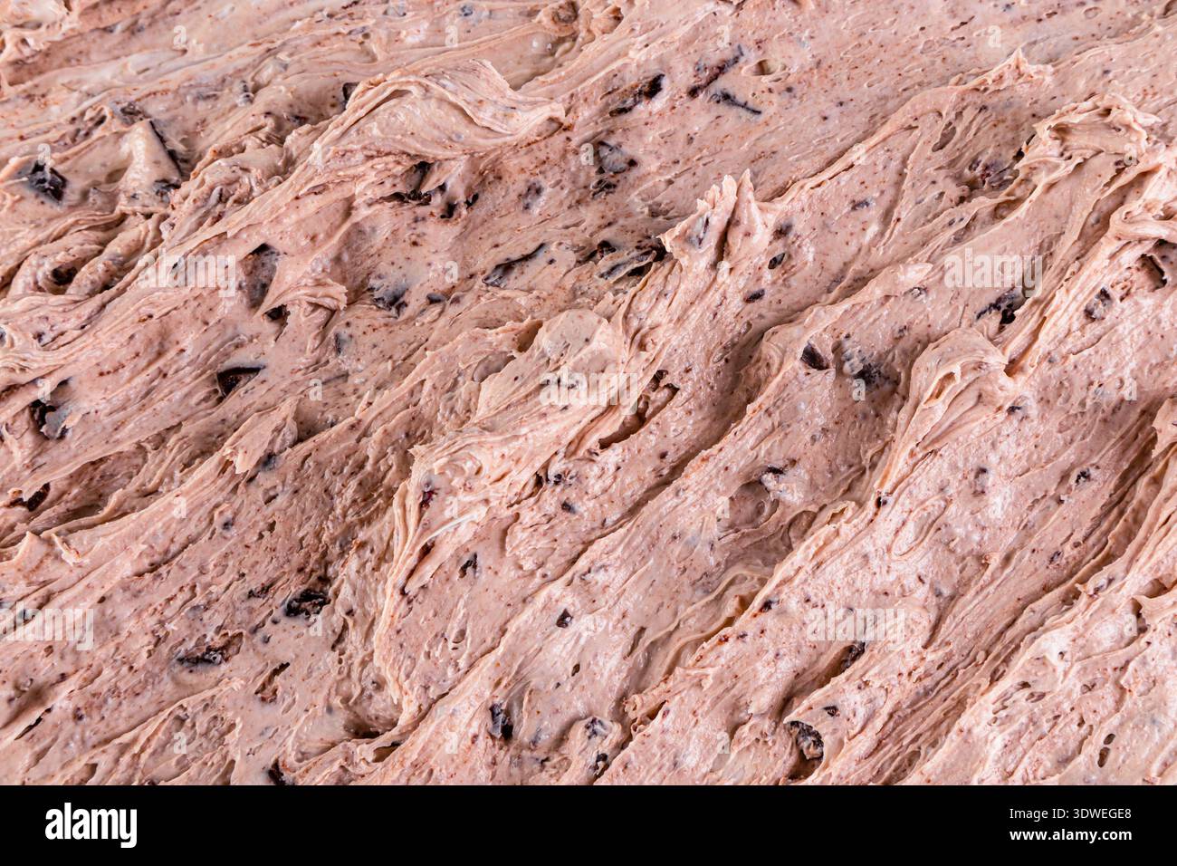 Primo piano di cremosi gelati al cioccolato con una consistenza ricca e turbolenta e pezzi di cioccolato, che mettono in mostra i dettagli intricati e l'appetitoso fascino Foto Stock