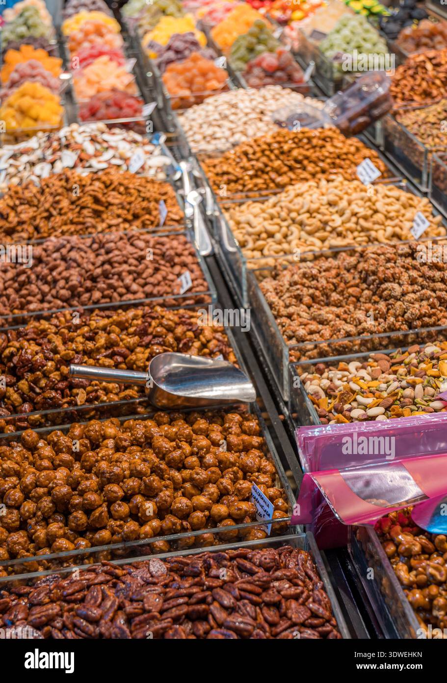Una variopinta gamma di frutta secca, noci e spuntini ordinatamente disposti in un'esposizione al mercato. Un motivo armonioso sfoggia texture e colori diversi. Foto Stock