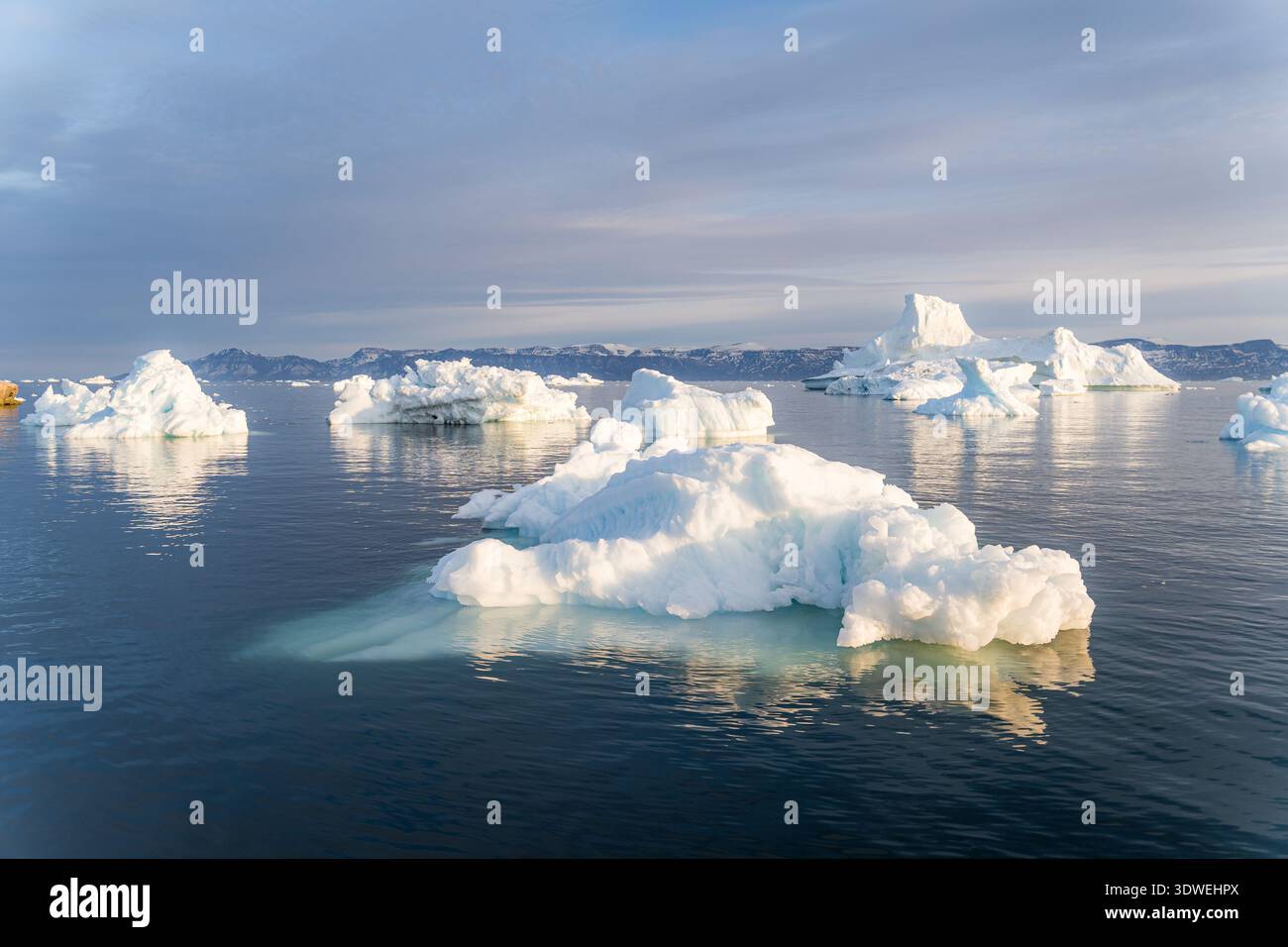 Gli iceberg vagano serenamente nelle tranquille acque di Saqqaq, in Groenlandia, sotto l'etereo bagliore del sole di mezzanotte, creando un'atmosfera incredibilmente pittoresca Foto Stock