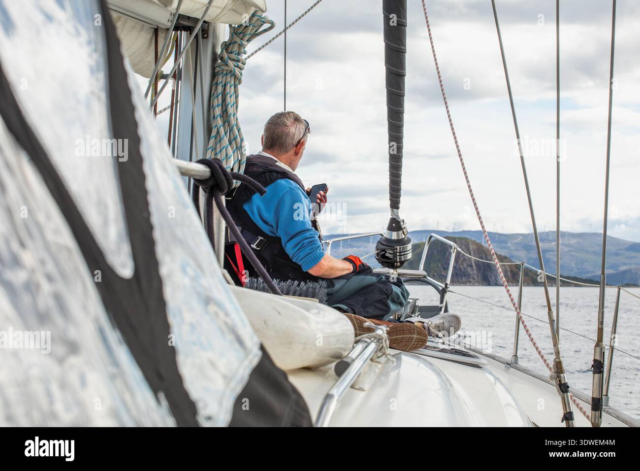 Un uomo gode di un'esperienza di navigazione serena su una barca in Norvegia, circondata da paesaggi pittoreschi e acque calme, mettendo in risalto la bellezza della nautica Foto Stock