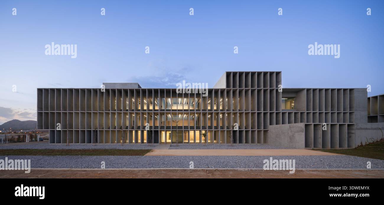 Un sorprendente edificio universitario brutalista con una facciata in cemento e una struttura a griglia. L'architettura presenta un design minimalista e geometrico Foto Stock
