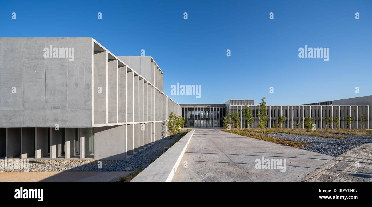 Un moderno campus universitario caratterizzato da un sorprendente esempio di architettura brutalista con ampie facciate in cemento e forme geometriche sotto un trasparente BL Foto Stock