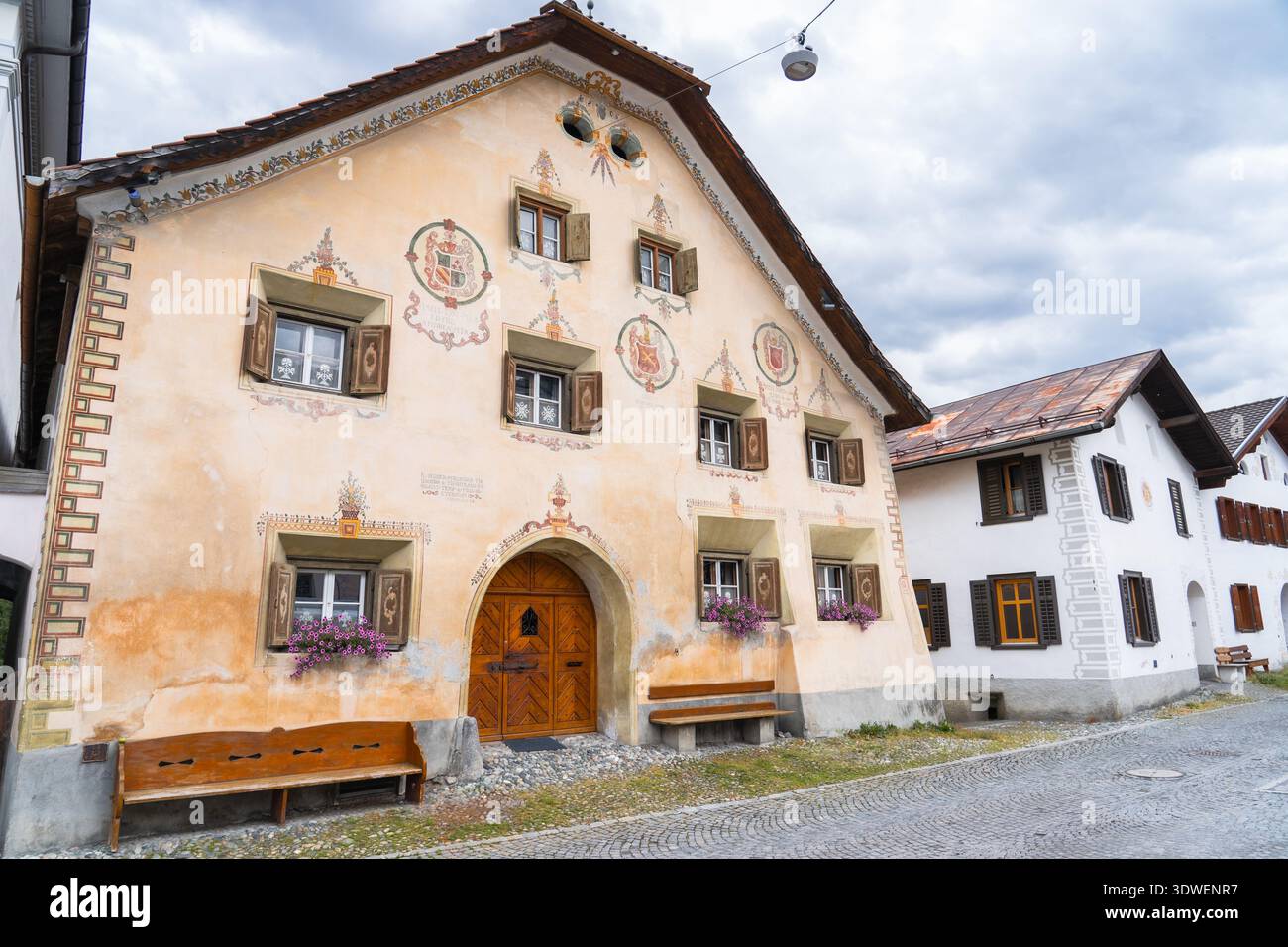 Il fascino del villaggio di Scuol, incastonato nelle Alpi svizzere. Questa immagine cattura le tradizionali case svizzere splendidamente adornate con dettagli intricati e alpe Foto Stock
