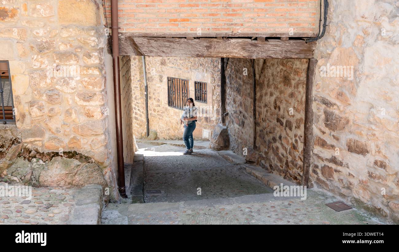 Una famiglia gode di una giornata pittoresca nel villaggio storico di Vinuesa, Soria. Una madre tiene il bambino in un vicolo di pietra, catturando il fascino dello spagnolo Foto Stock