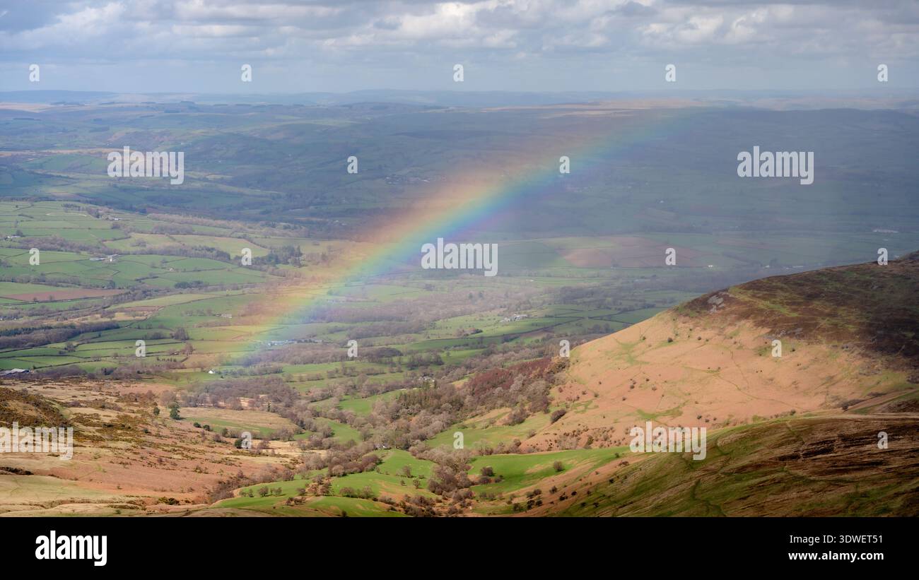 Un vivace arcobaleno sulle lussureggianti colline e valli del Parco Nazionale di Brecon Beacons. Questo splendido paesaggio cattura la serena bellezza di Foto Stock