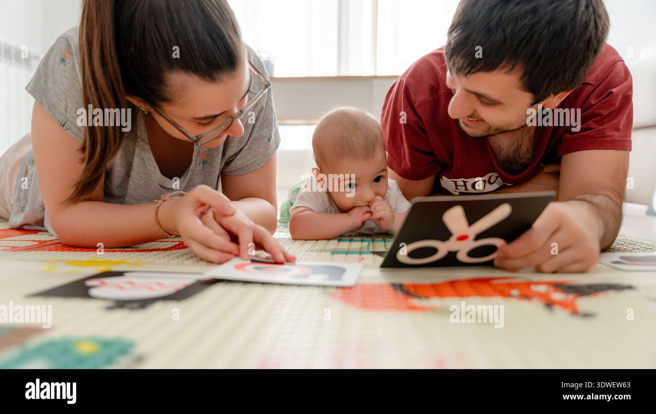 I genitori e il loro bambino si dedicano all'apprendimento precoce utilizzando carte ad alto contrasto. Il tempo di gioco interattivo è incentrato sul miglioramento della stimolazione visiva del bambino Foto Stock