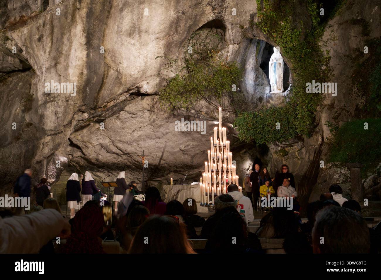 I fedeli visitano la grotta di Lourdes Foto Stock