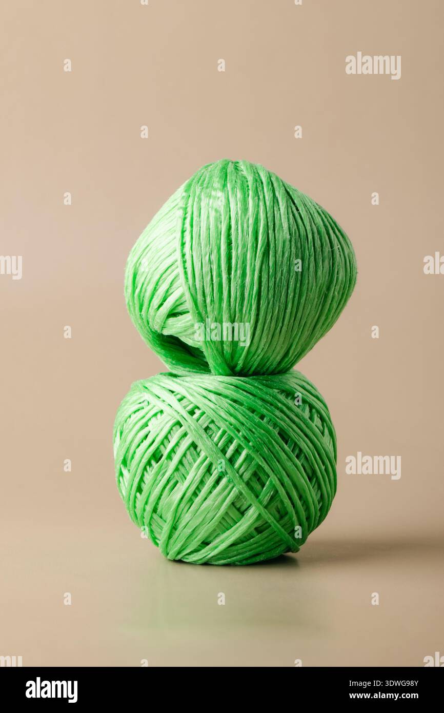 Una palla di tessuto sintetico in poliestere riciclato verde su sfondo beige. Vita verde, riciclaggio di plastica, riutilizzo Foto Stock