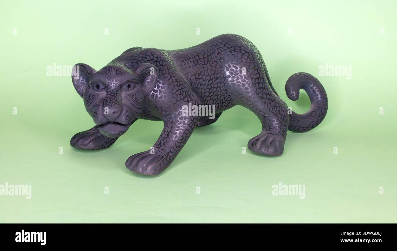 Statua in ceramica nera di una jaguar isolata su sfondo verde Foto Stock