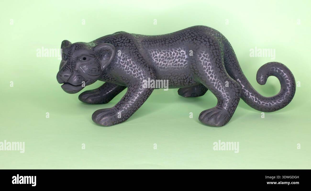Statua in ceramica nera di una jaguar isolata su sfondo verde Foto Stock
