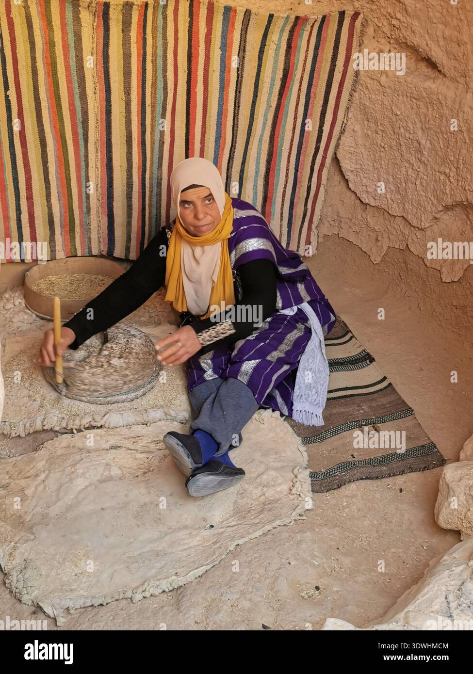 Le donne berbere aprono la loro casa sotterranea troglodita nella grotta ai turisti di Matmata, Tunisia, e dimostrano di fare il pane della tabouna. - Immagine stock catturata con smartphone