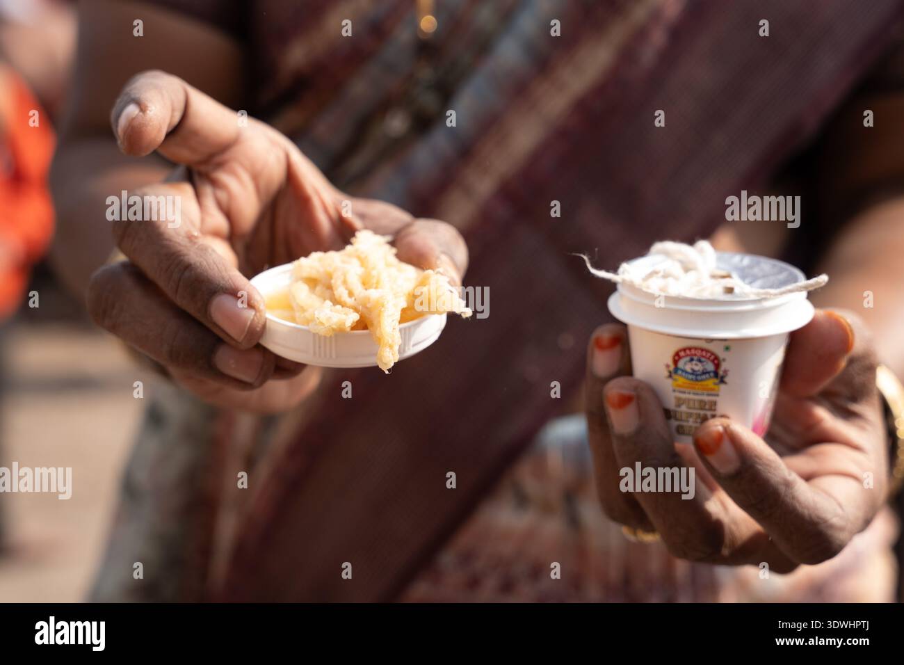 Primo piano di mani che tengono in mano il cono e il portabandiera tradizionale di incenso a Varanasi, in India, con oggetti rituali culturali. Foto Stock