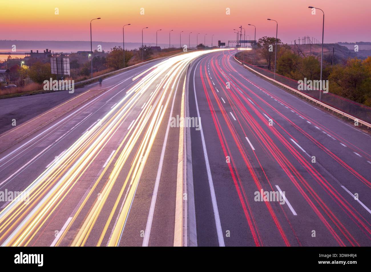 Autostrada suburbana dopo il tramonto. Percorsi leggeri da fari e luci di posizione posteriori di traffico pesante in Ucraina Foto Stock