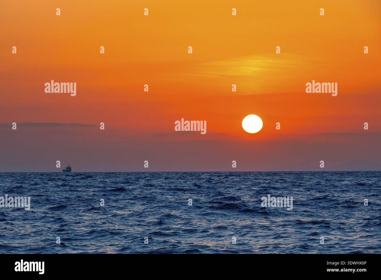 Mare sconfinato. Incredibile tramonto arancione. Piccola nave a bordo all'orizzonte Foto Stock