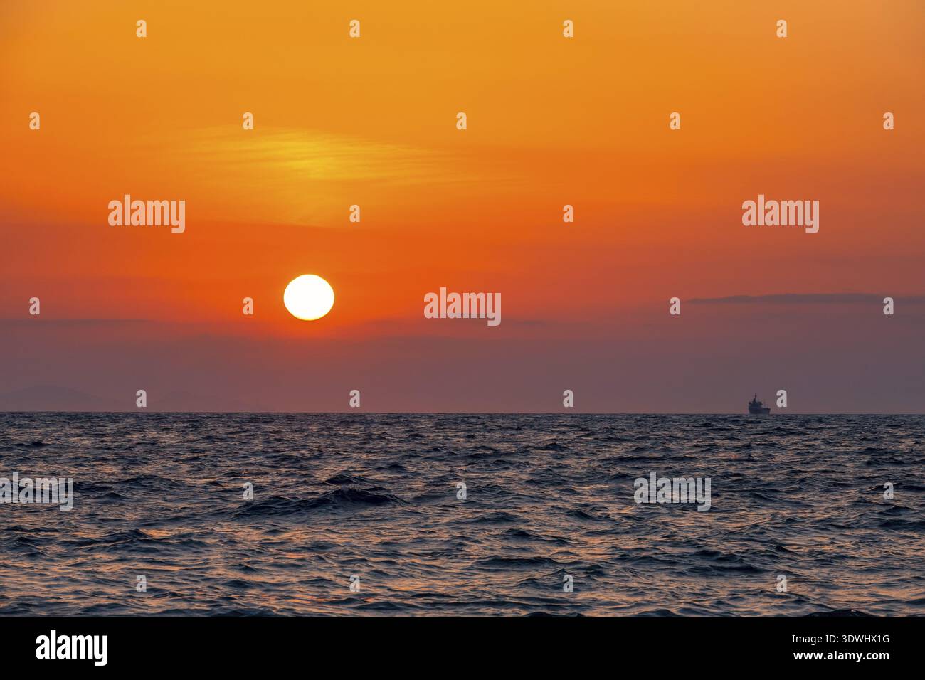 Mare sconfinato. Incredibile tramonto rosso. Piccola nave a bordo all'orizzonte Foto Stock