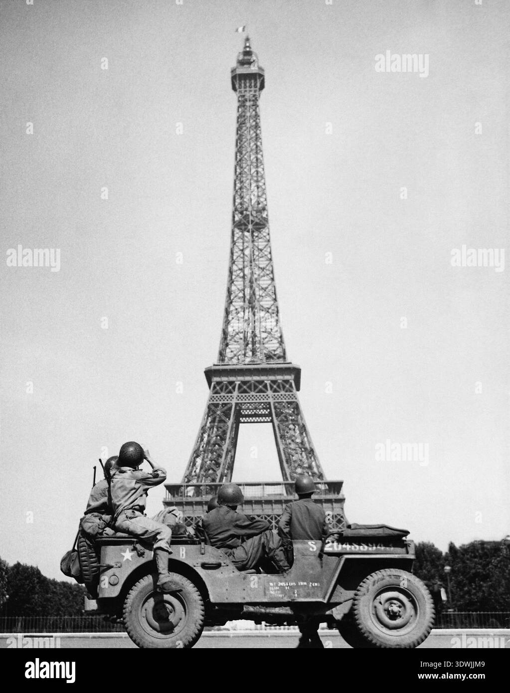 Questa potente fotografia del 1944 cattura i soldati americani che si fermano nella loro jeep per ammirare la Torre Eiffel, sulla quale la bandiera tricolore francese vola orgogliosamente dopo la liberazione di Parigi. L'immagine funge da simbolo commovente di vittoria e libertà nelle immediate conseguenze della seconda guerra mondiale Foto Stock