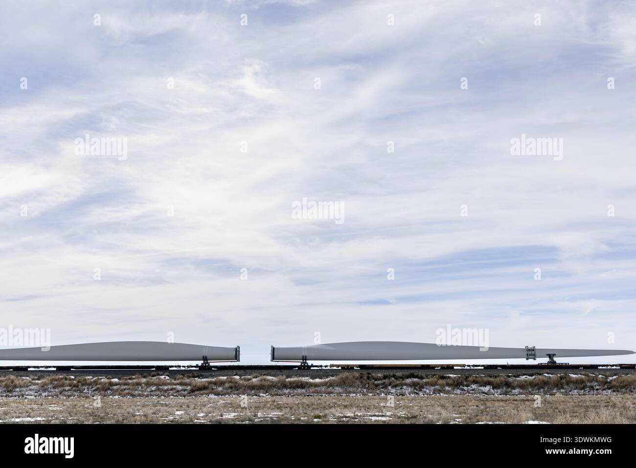 Le pale dei mulini a vento vengono trasportate in vagoni sotto il cielo Foto Stock