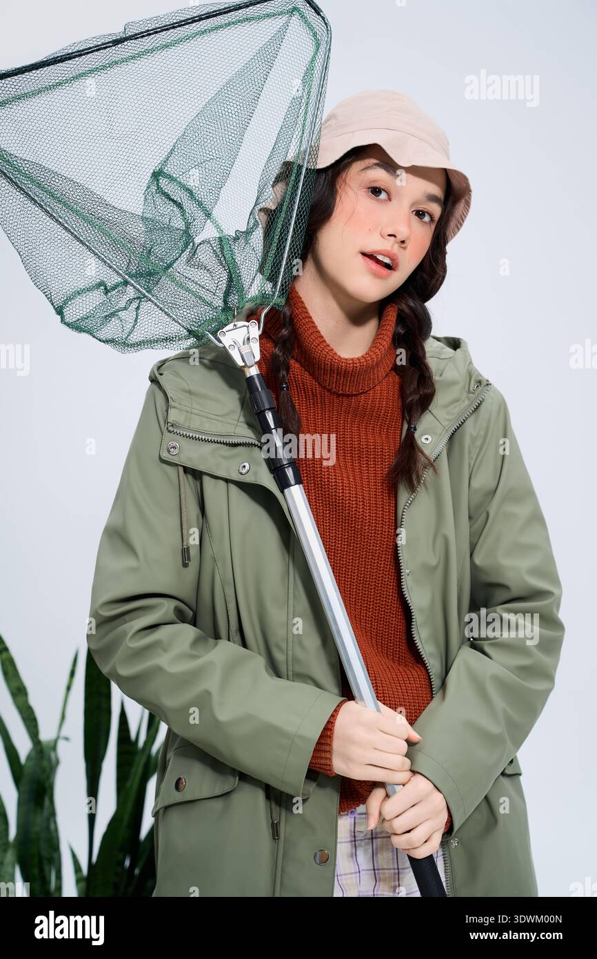 Una giovane donna vestita di attrezzatura da pesca posa con fiducia la canna da pesca e la rete. Foto Stock