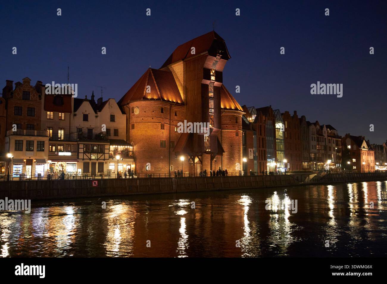 porta della gru del vecchio porto illuminata stary zuraw portowy brama zuraw sulle rive del centro storico del fiume motlawa danzica, polonia Foto Stock