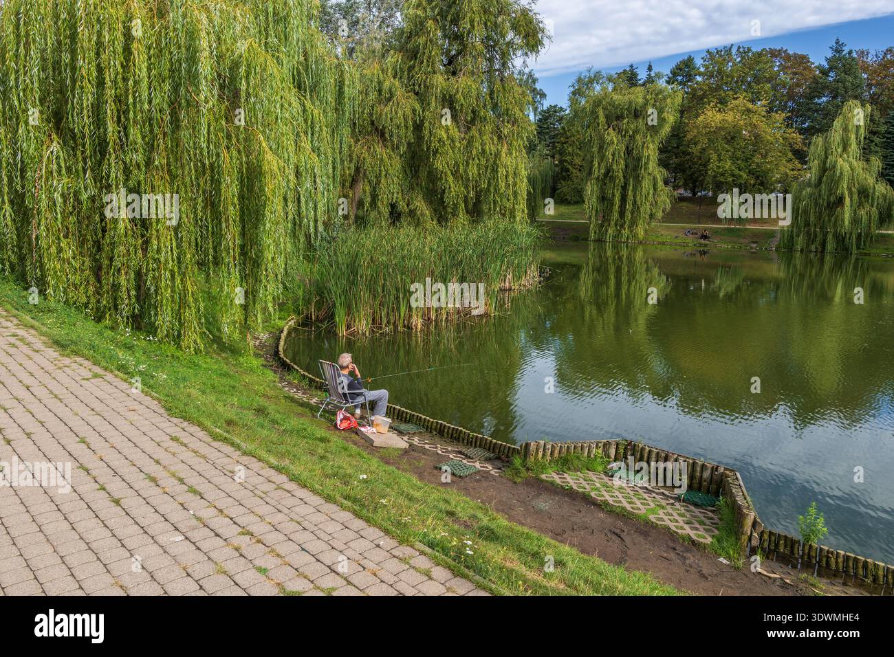 Pescatore singolo nello stagno del Parco Moczydlo nella città di Varsavia, Polonia. Foto Stock