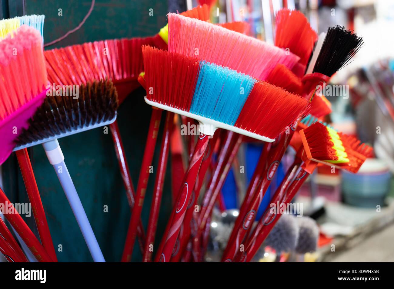 Spazzatrici colorate esposte in un bancone del mercato, vivaci strumenti di pulizia messi in vendita in un ambiente urbano Foto Stock