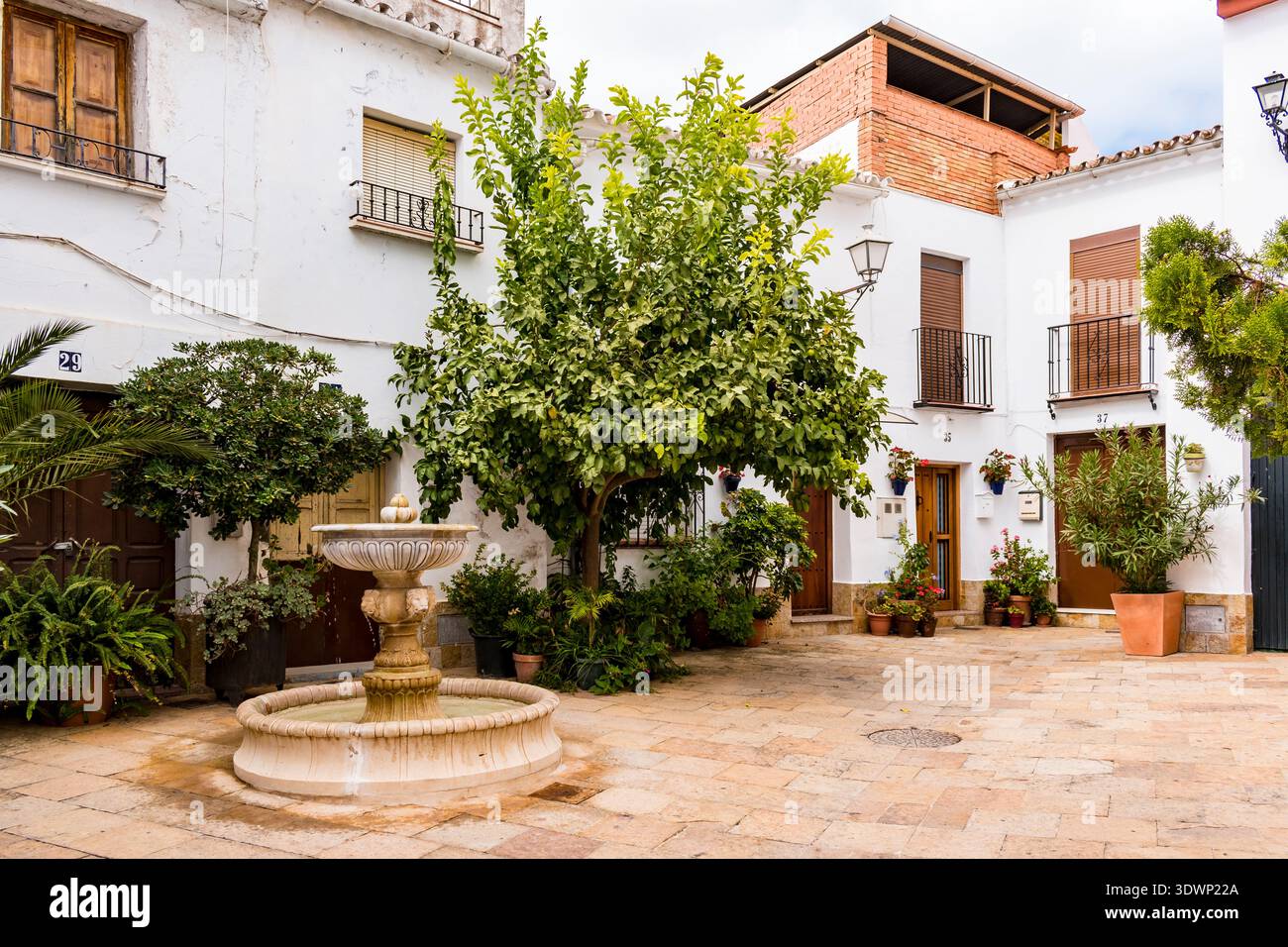 Piccola piazza con vasi di fiori e alberi ombreggiati. Yunquera, Málaga, Andalucía, Spagna, Europa Foto Stock