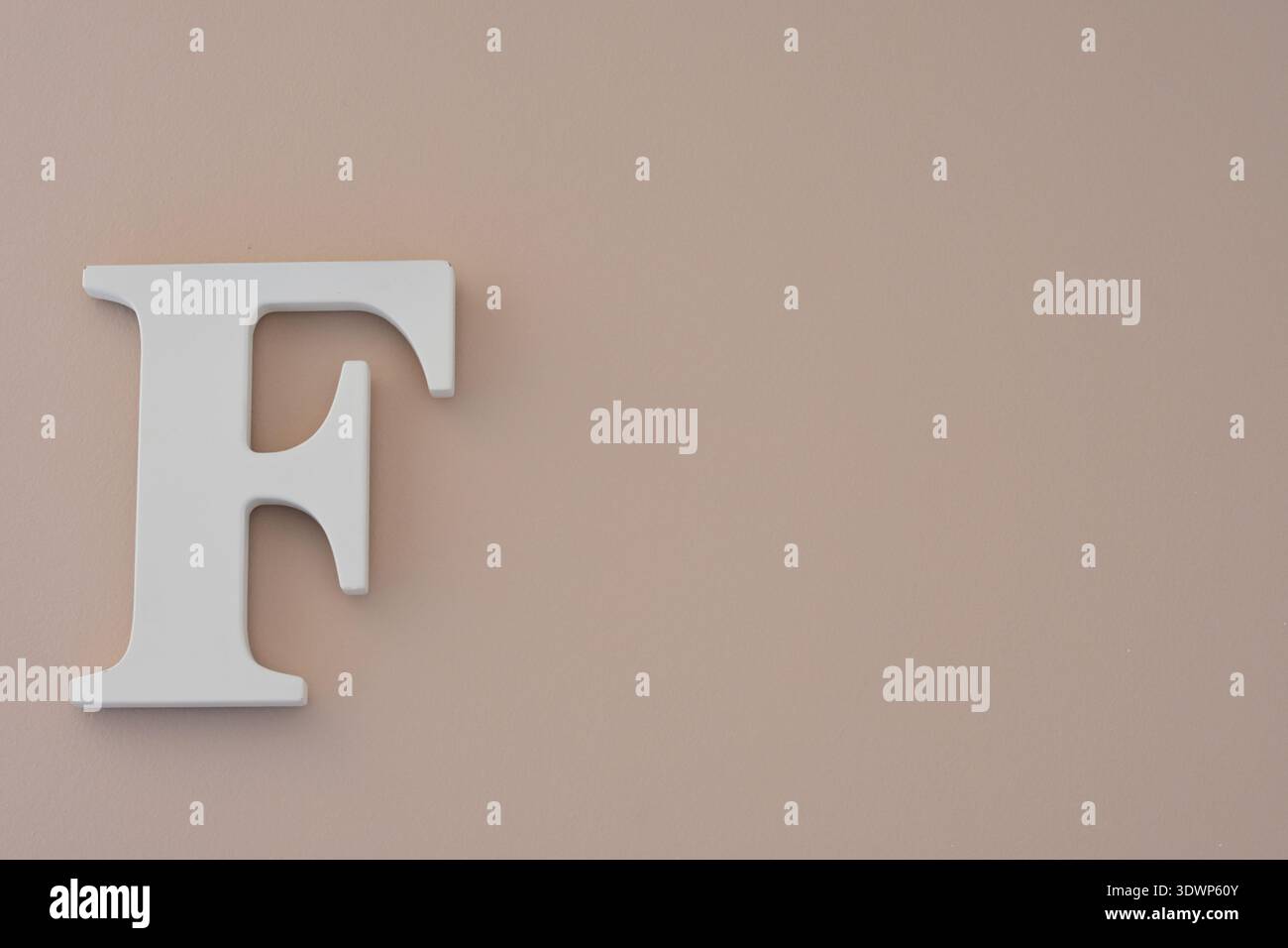 Lettera F in legno bianco sulla parete beige: Decorazioni minimali a forma di alfabeto Foto Stock