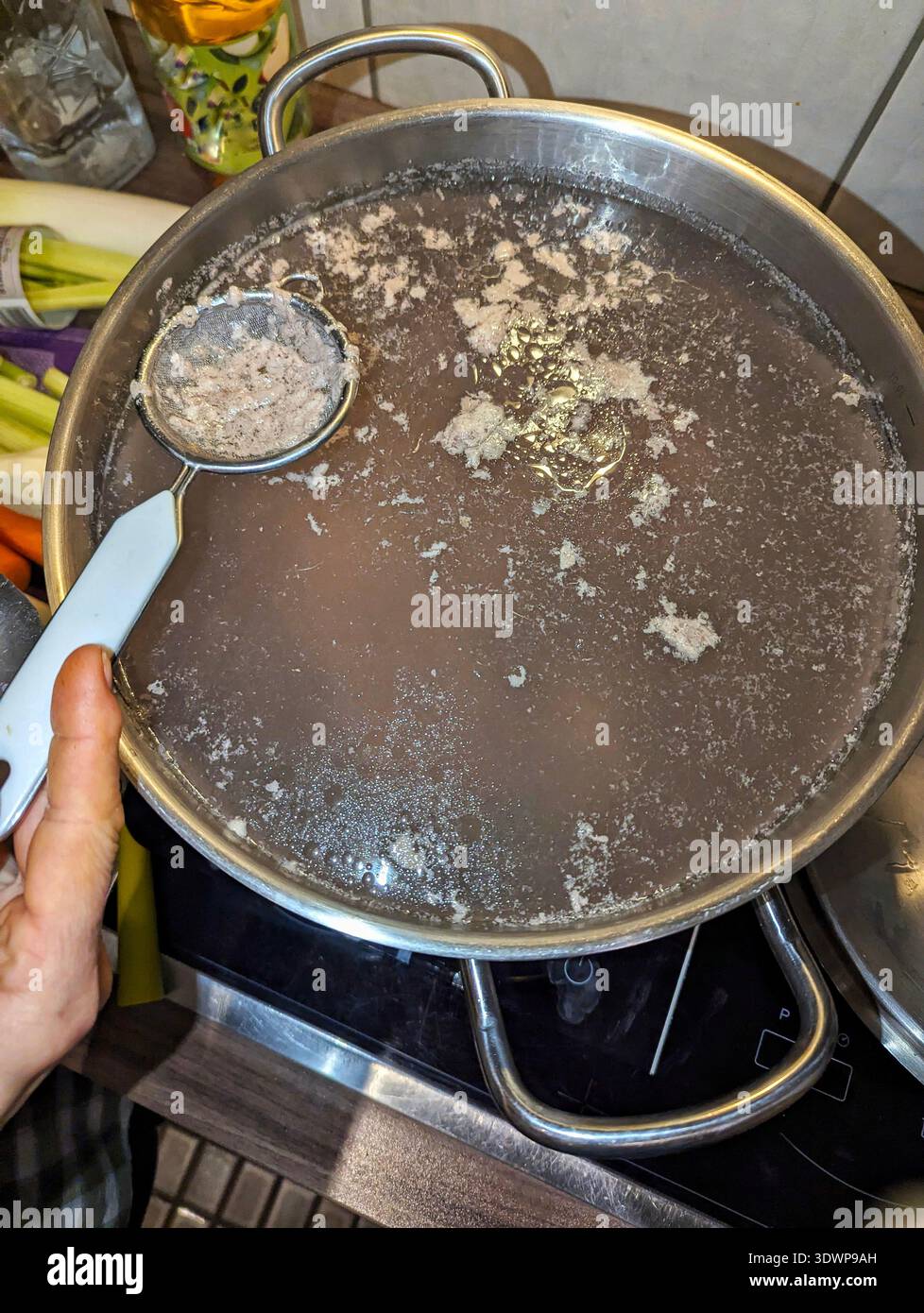 Skimming Cloudy Broth. Pratica dell'eliminazione della schiuma nel processo di cottura del brodo osseo. Dimostrazione della tecnica pratica della cucina per una maggiore chiarezza delle scorte Foto Stock
