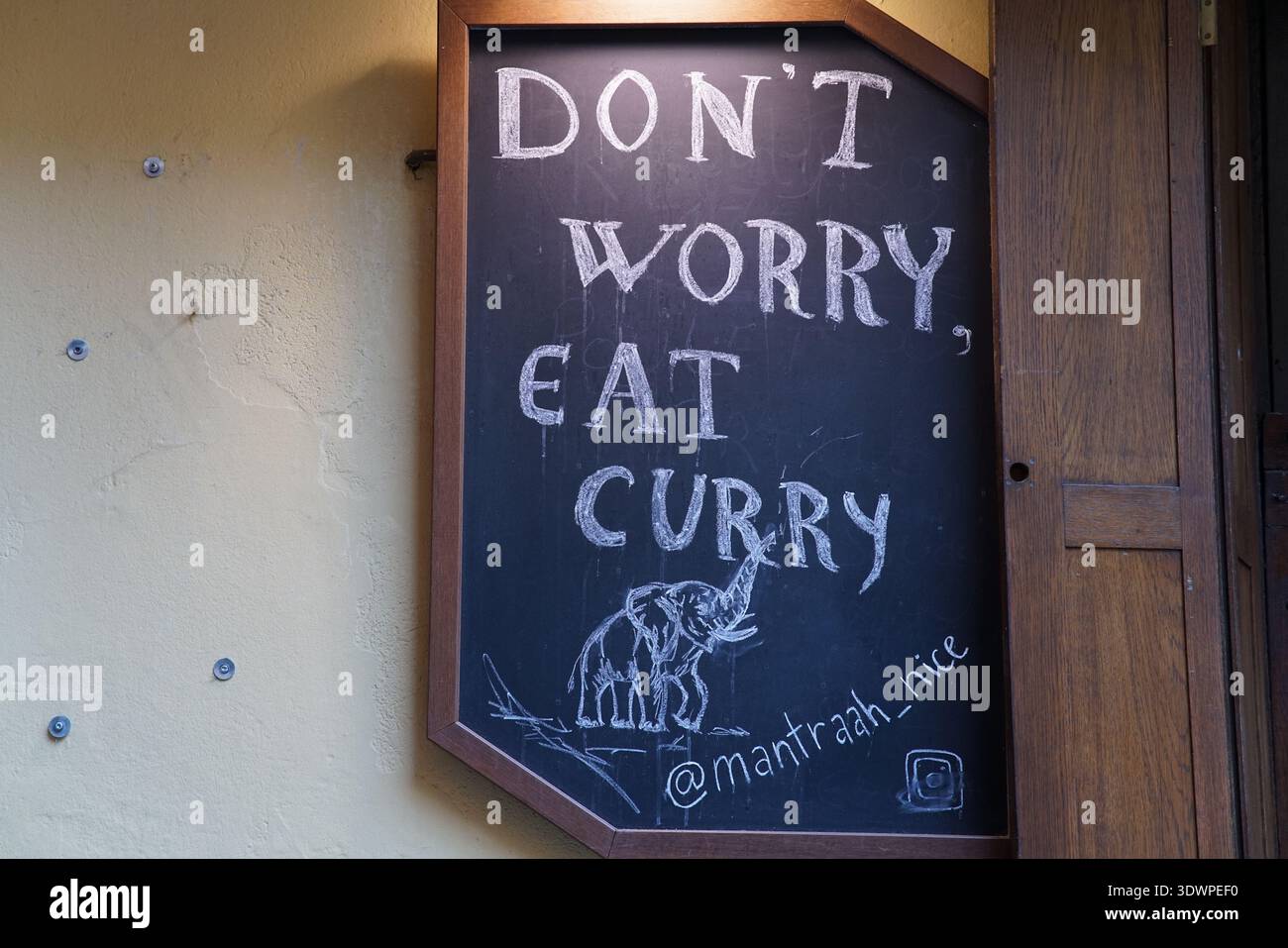Il cartello sulla lavagna a Mantrah a Nizza recita "NON PREOCCUPARTI, MANGIA CURRY" con un allegro disegno di elefante, appeso fuori da un ristorante indiano in città Foto Stock