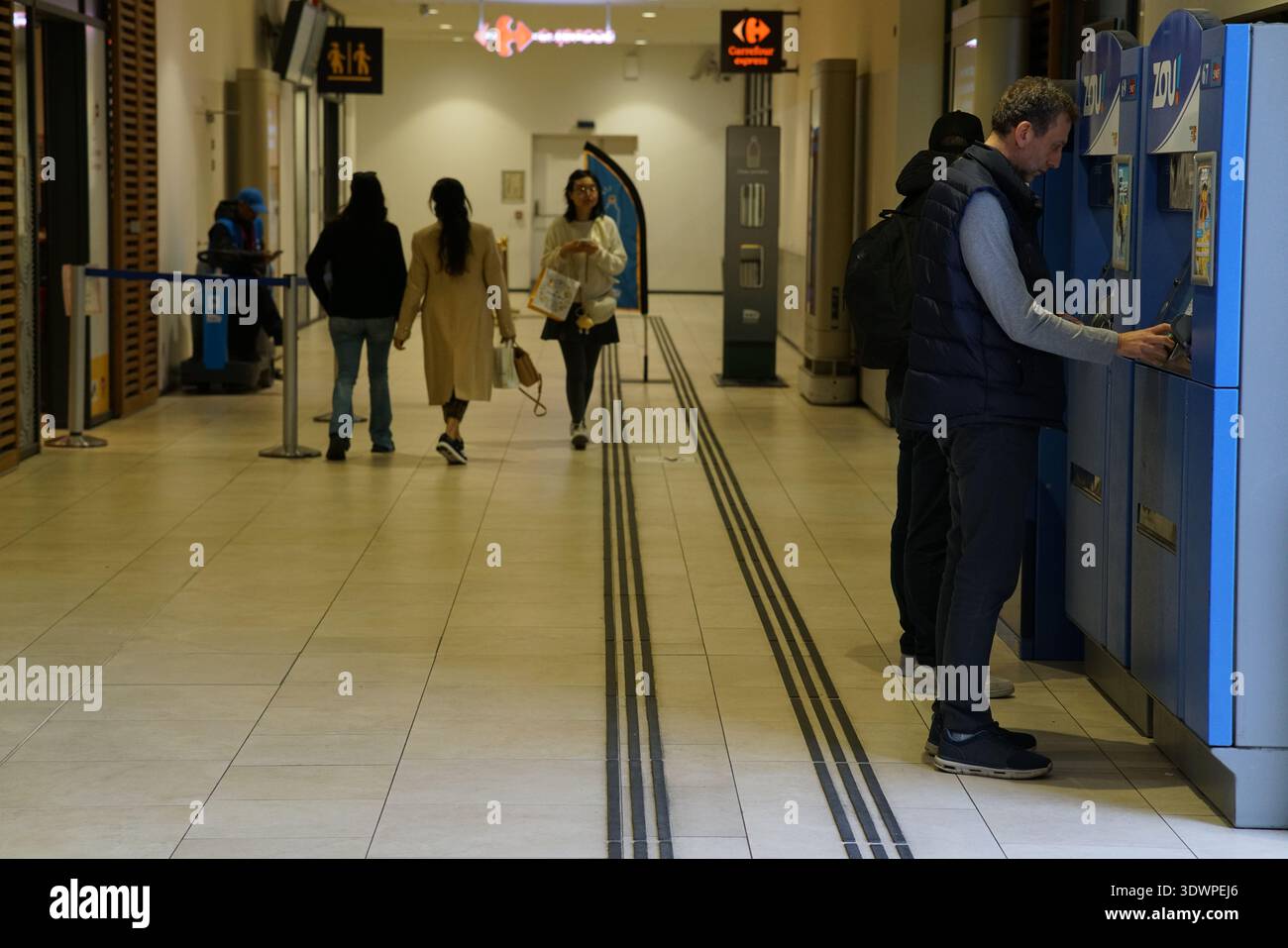 Corridoio affollato alla stazione ferroviaria di Nice Ville, dove un viaggiatore paga presso gli armadietti blu, mentre altri camminano verso piattaforme con borse e zaini. Foto Stock