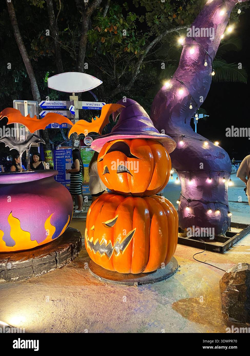 Phuket, Thailandia - 29 ottobre 2025: Le decorazioni di Halloween includono una zucca arancione sorridente che indossa un cappello da strega, un calderone viola e tr illuminato Foto Stock