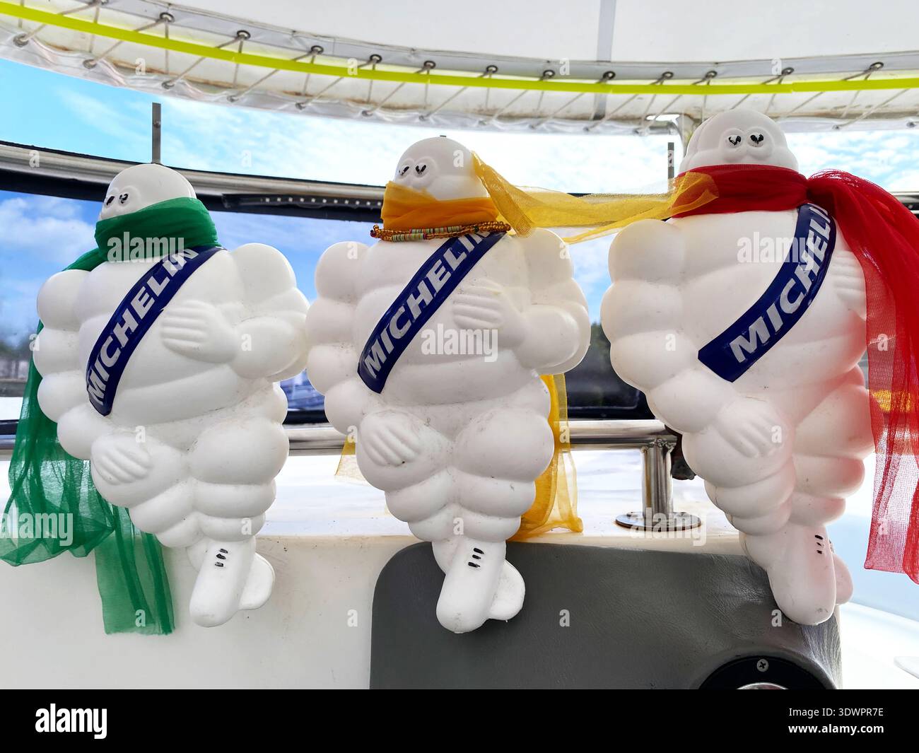 Phuket, Tailandia - 30 ottobre 2025: Tre gonfiabili Michelin Man con foulard colorate sono posizionati su un motoscafo nella panoramica coasta Tailandese Foto Stock