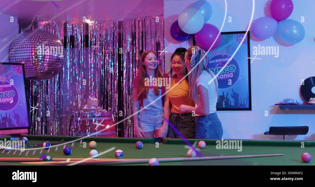 Tre donne sorridenti che indossano top rossi, arancioni e bianchi con jeans al tavolo da biliardo e ballo da discoteca Foto Stock