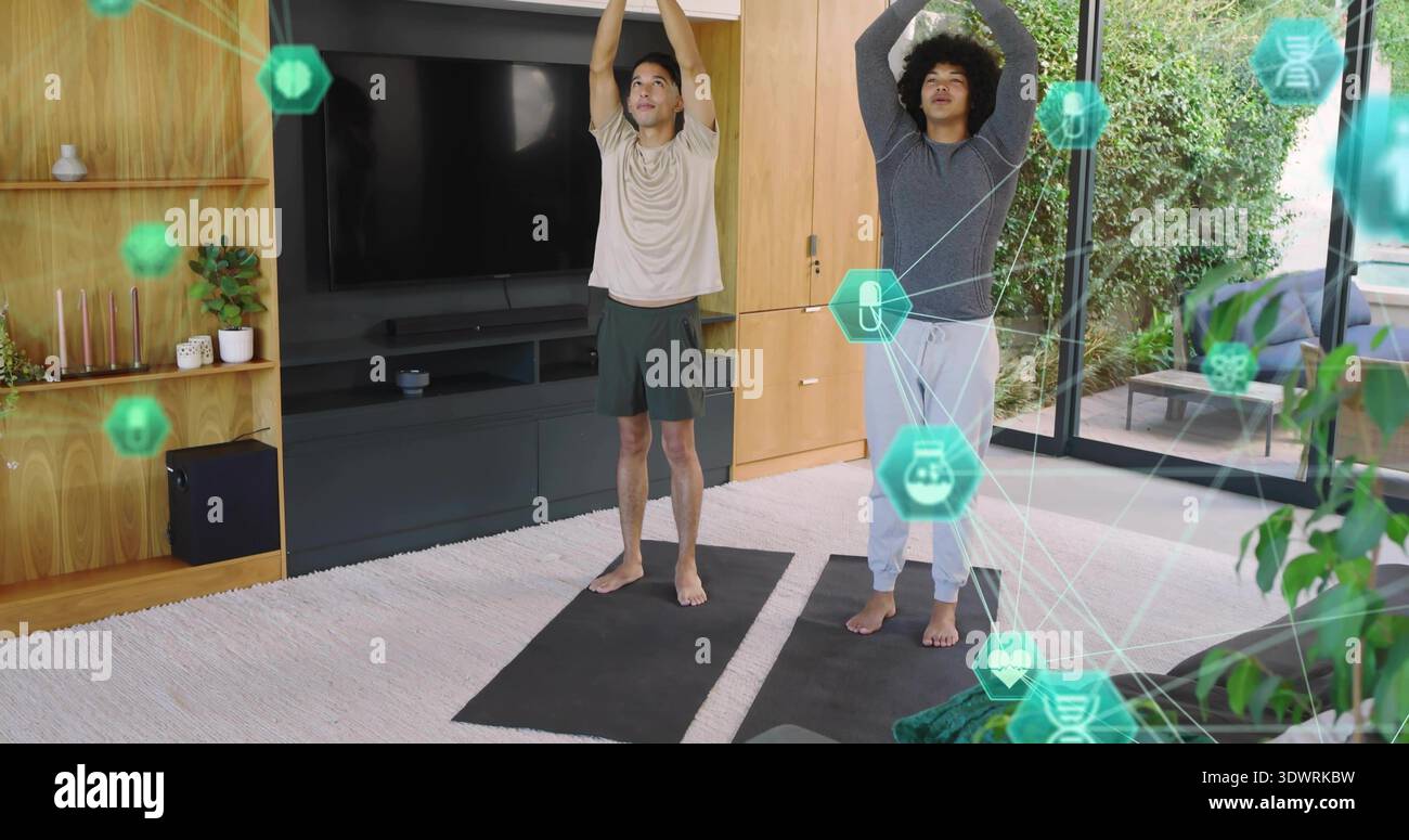 Due adulti indossati in modo atletico su tappetini da yoga nel soggiorno, con rivestimento verde Foto Stock