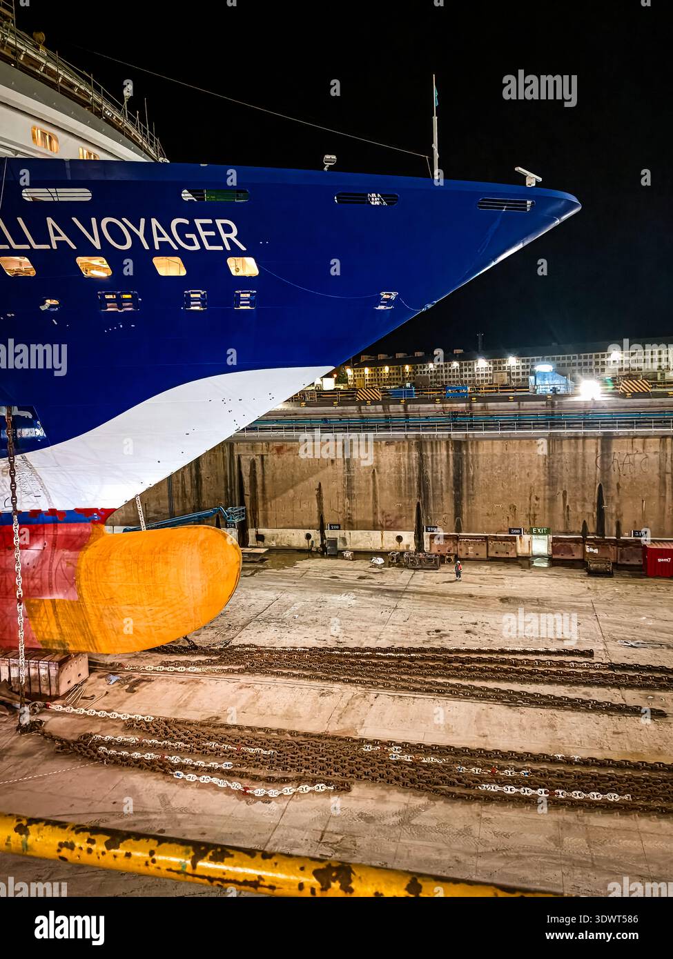 Prua della nave da crociera Marella Voyager nel bacino di carenaggio durante la manutenzione notturna nel porto di Cadice, Spagna, con elica visibile e nave industriale Foto Stock