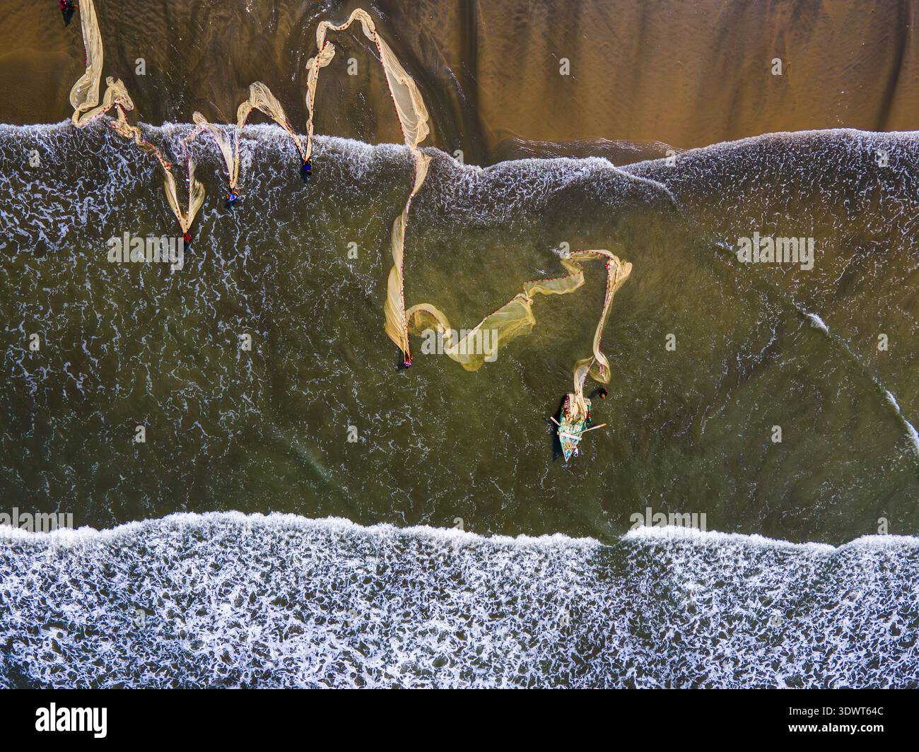Cox's Bazar, Bangladesh - 16 maggio 2024: Vista aerea delle barche da pesca che gettano reti nelle acque scintillanti e striate dalle onde, creando schemi contro Foto Stock