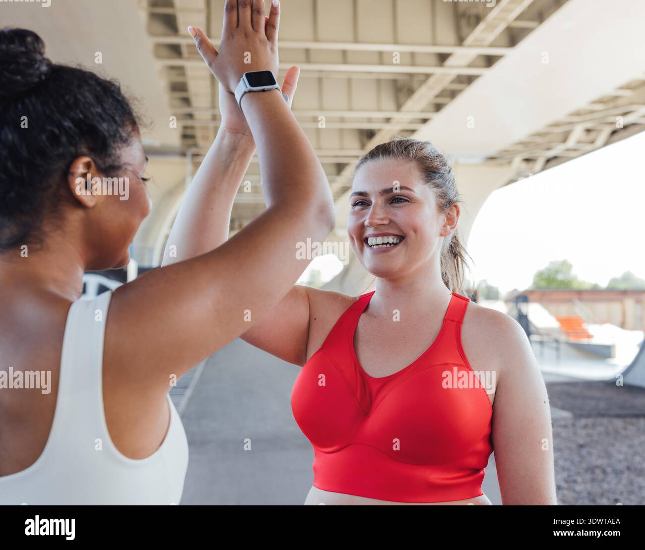 Due donne più grandi ne danno cinque dopo un intenso allenamento. Una donna sorridente e di grandi dimensioni che ne dà cinque al suo compagno di fitness. || modello rilasciato Foto Stock