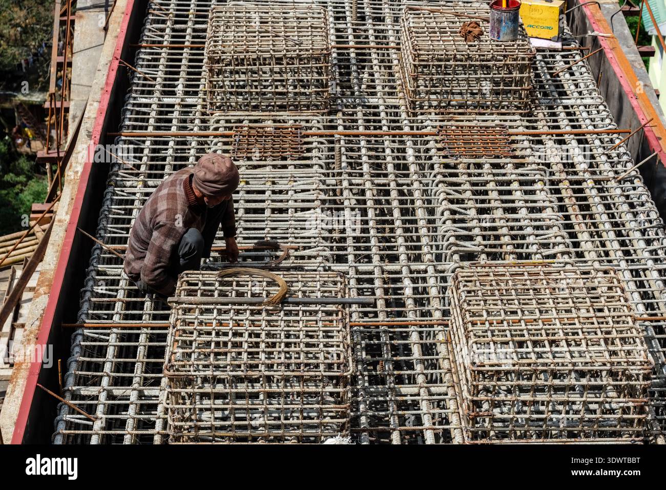 Un operaio edile installa barre di rinforzo in acciaio per una lastra di cemento in un cantiere a Shimla. Foto Stock