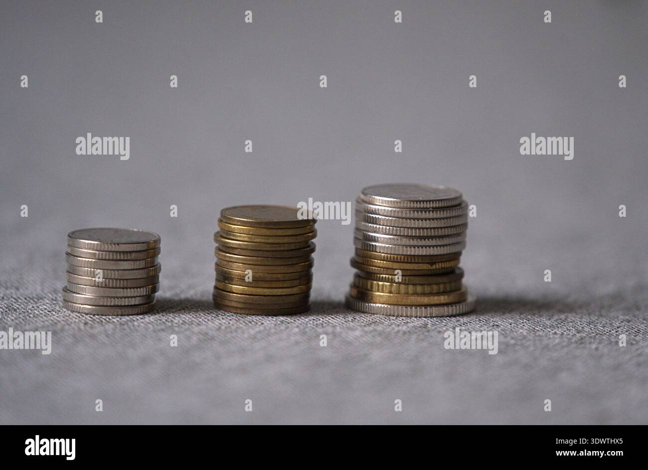 Tre pile di monete di diverse altezze, che spesso simboleggiano la crescita di risparmi, investimenti o processi economici. Foto orizzontale Foto Stock