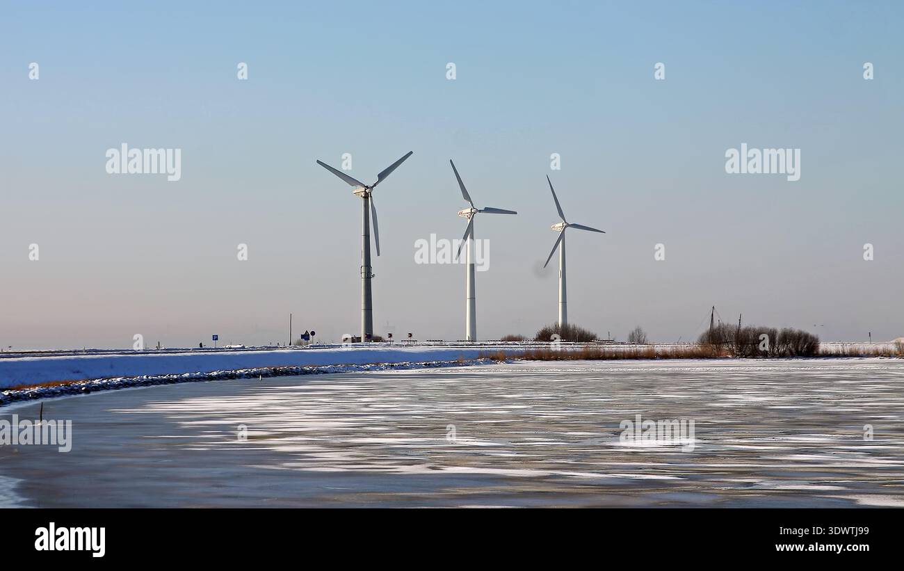 Mulini a vento in fila sull'acqua ghiacciata in inverno Foto Stock
